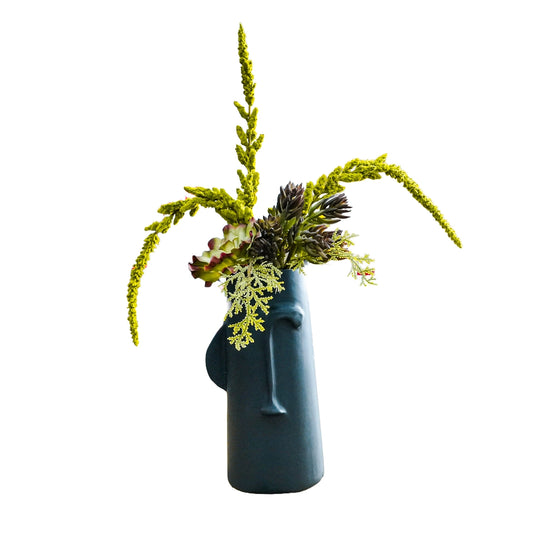 A black face shaped vase with succulent plants