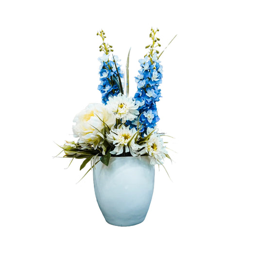 Floral arrangement with blue and white flowers in a light blue vase on a white background