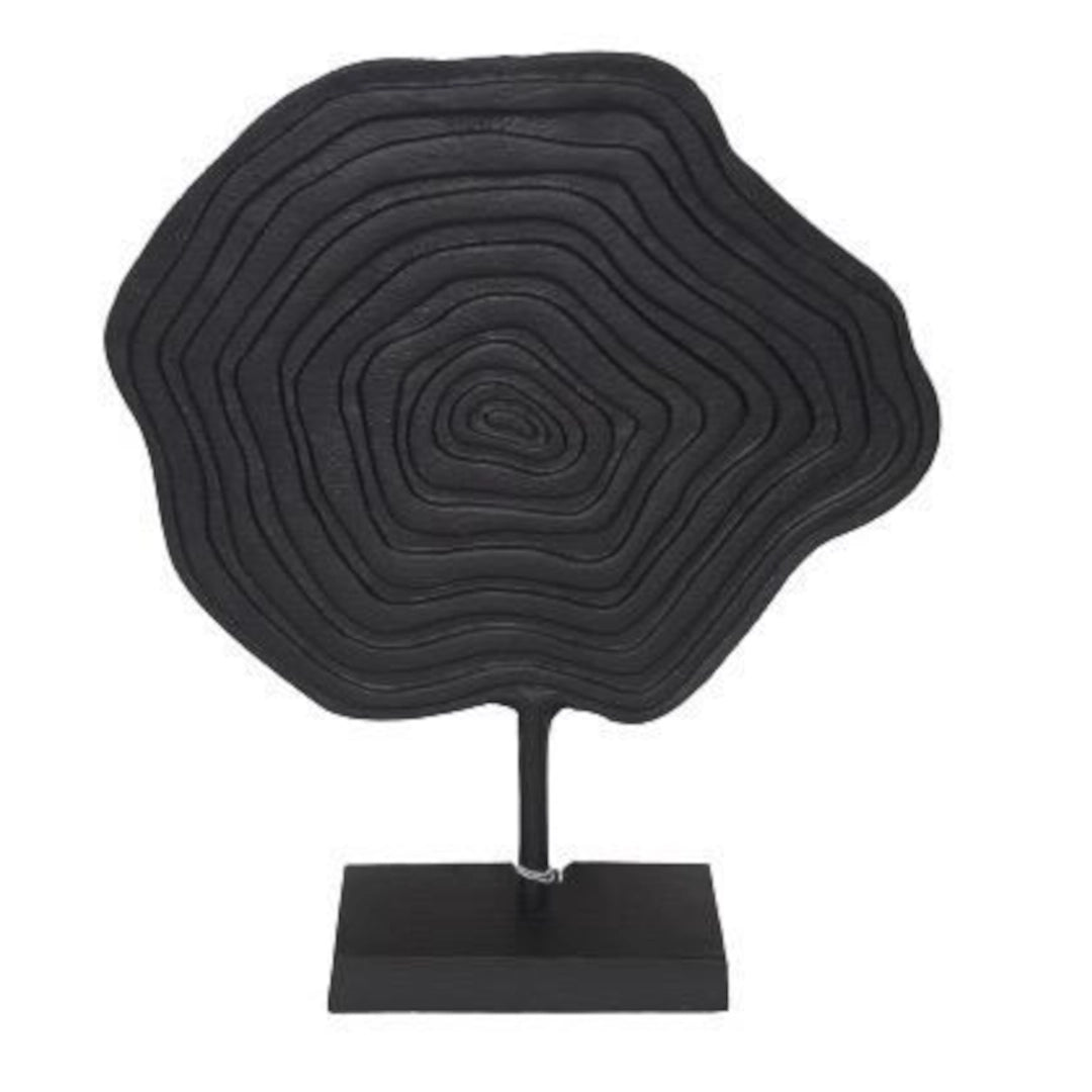 Black circular sculpture on a stand against a white background