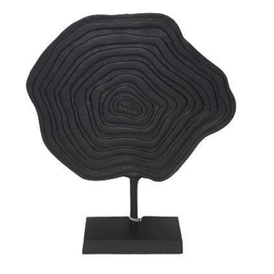Black circular sculpture on a stand against a white background