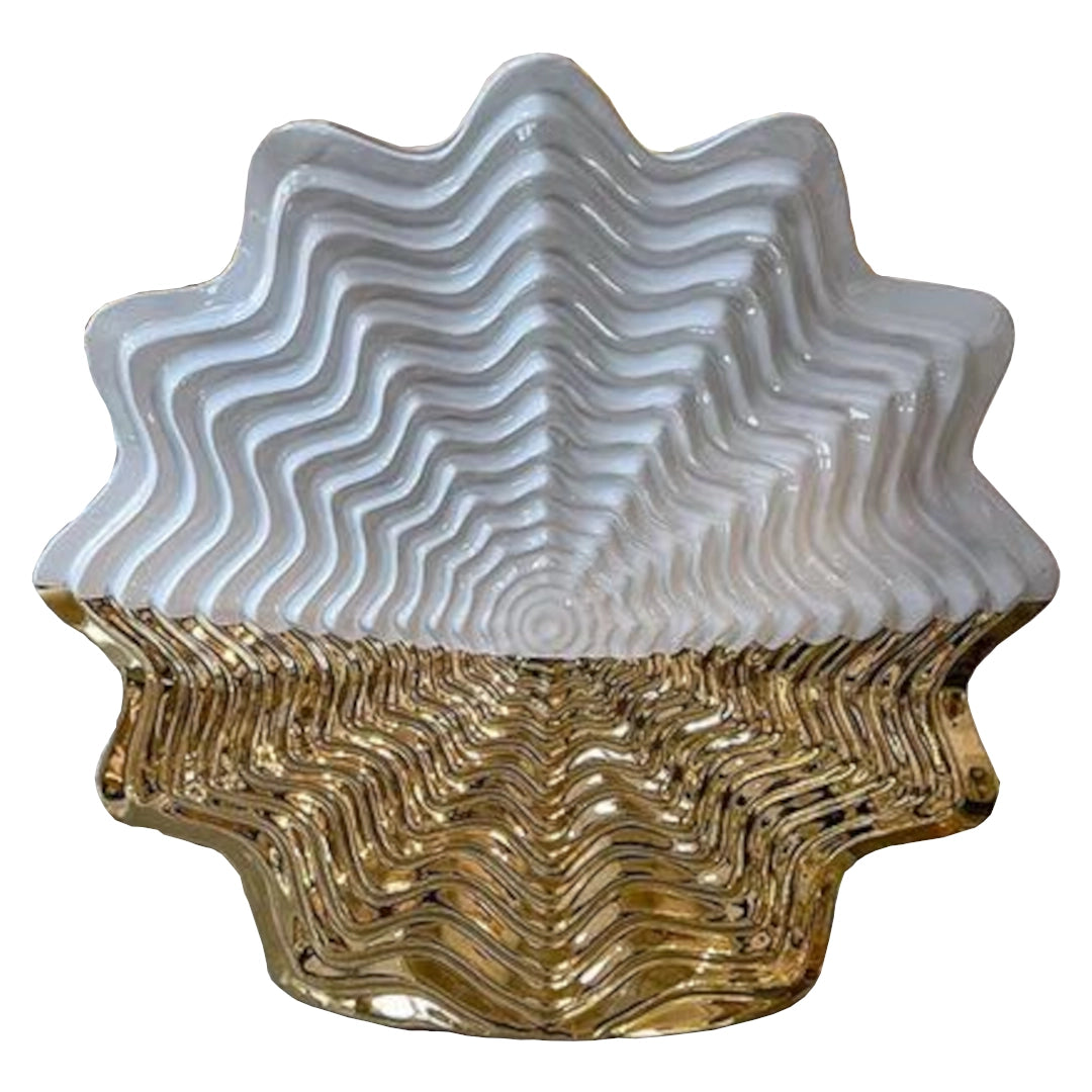 Decorative shell ornament with wavy design in white and gold on a white background