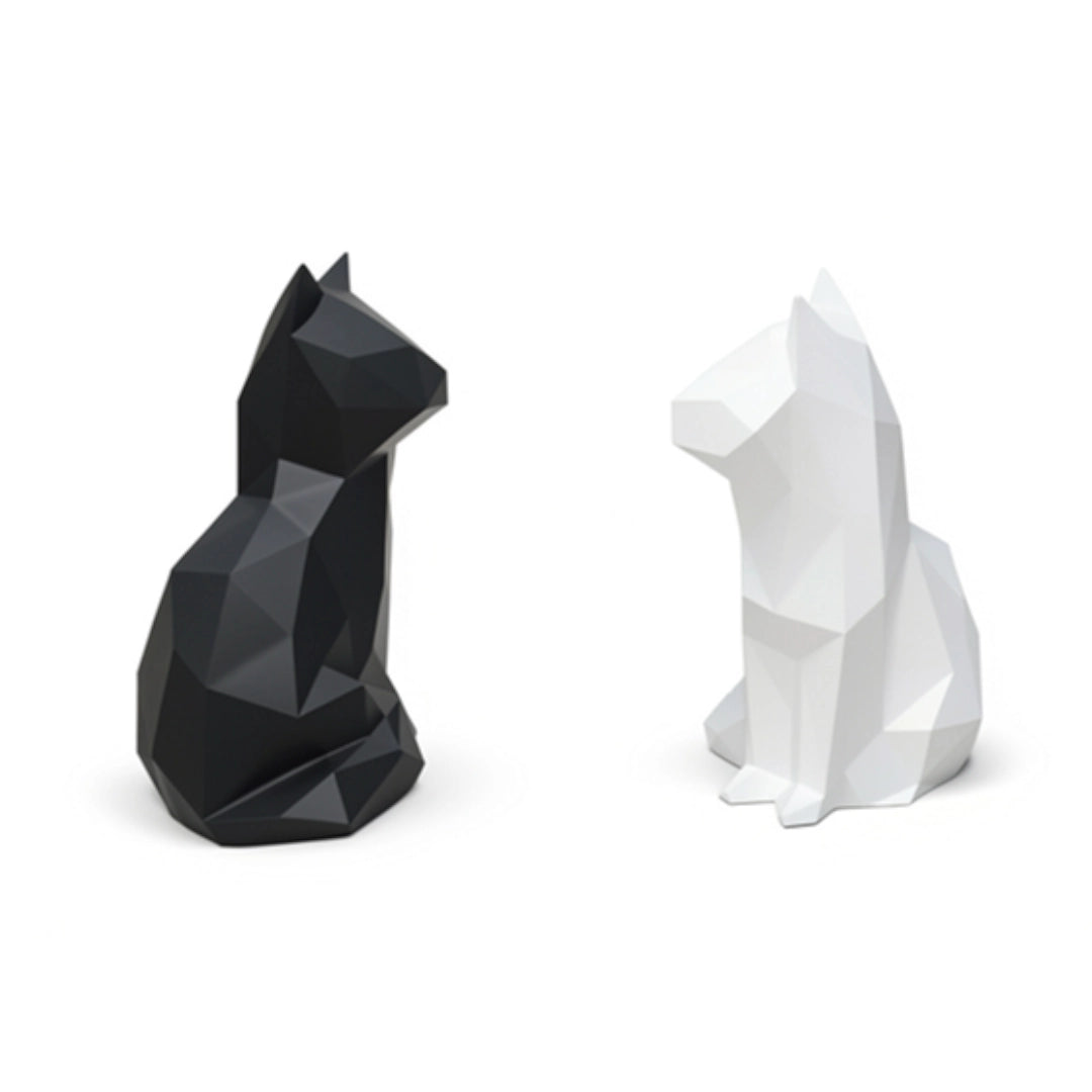 Two cat statues, one black and one white, on a white background